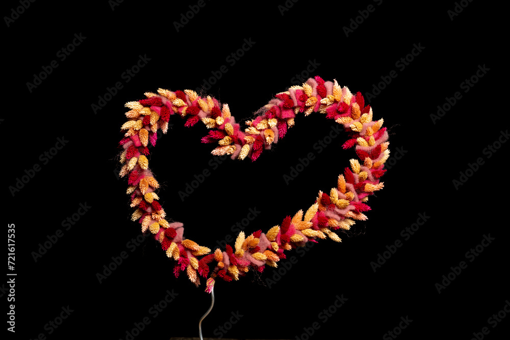 dried flowers tied as heart shape on black background with space for text