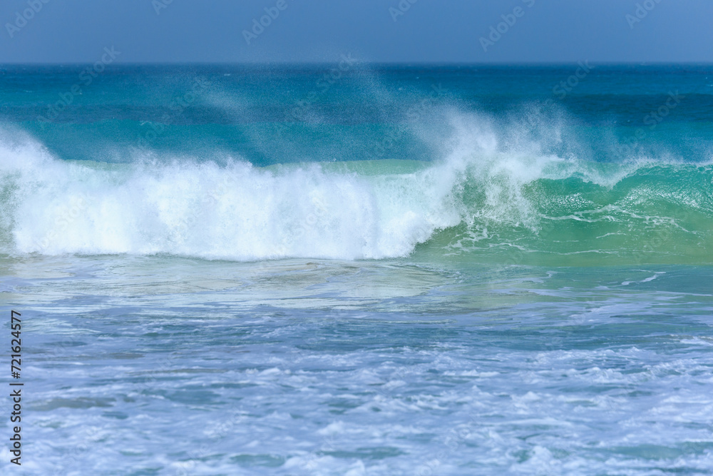 Wave with azure water and white foam approaches on a windy day at Boa Vista's beach, Cape Verde.