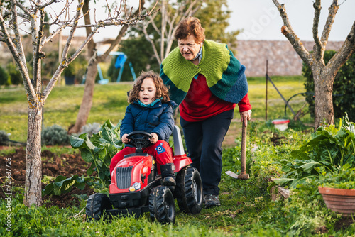 grandmother and grandson playing with a tractor in the garden at home