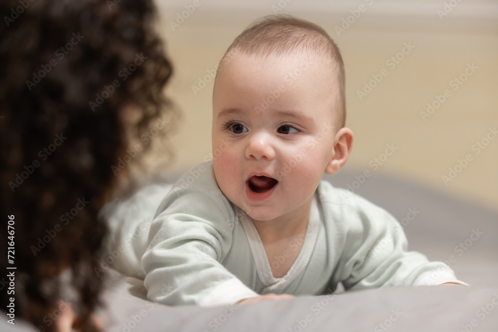Baby boy on a bed smiling and happy. Close up portrait. mother