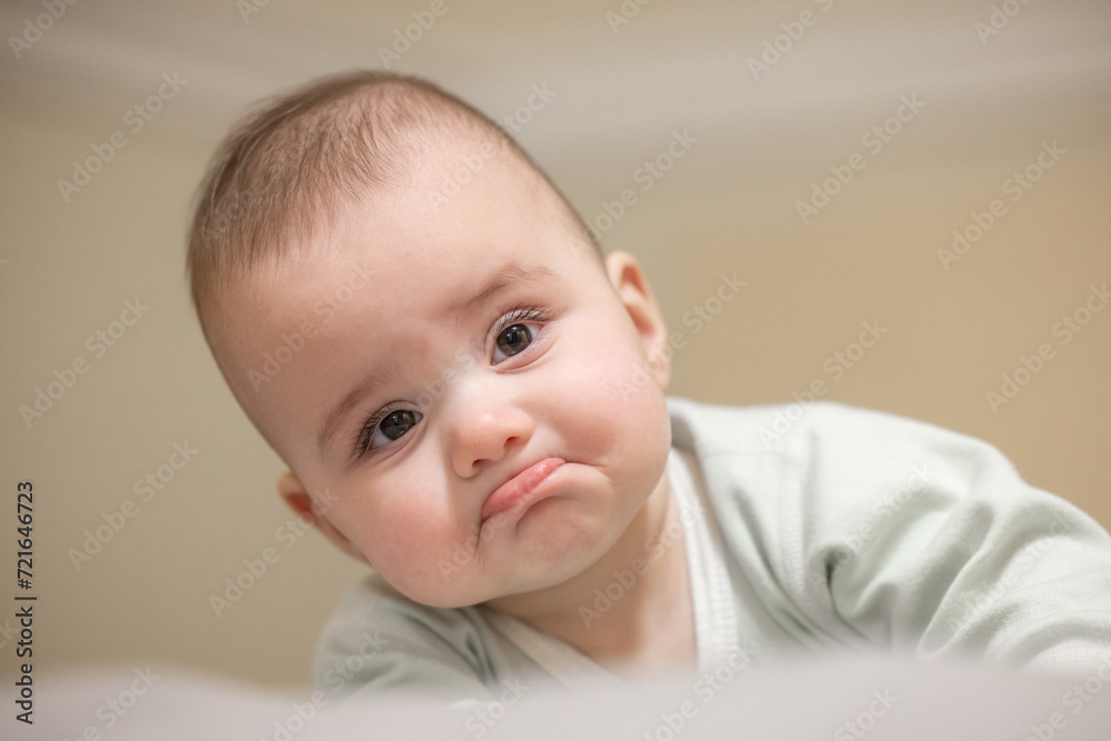 Baby boy on a bed frowning in disapproval. Close up portrait