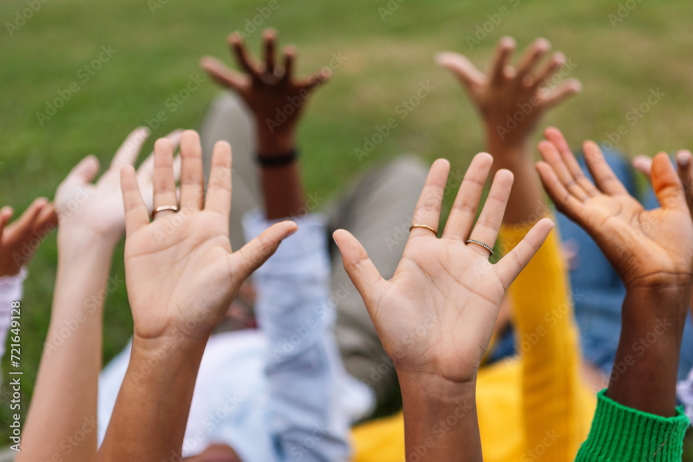 Closeup view of united group of diverse women raising hands lying together at city park. Hope, support and volunteer community concept. Closeup view of united group of diverse women raising hands lying together at city park. Hope, support and volunteer community concept.