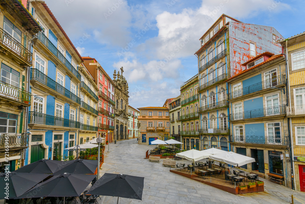 Shops and sidewalk cafes at the colorful Largo São Domingos square with the Porto Misericórdia Church in view in the historic Ribeira district of Porto Portugal.