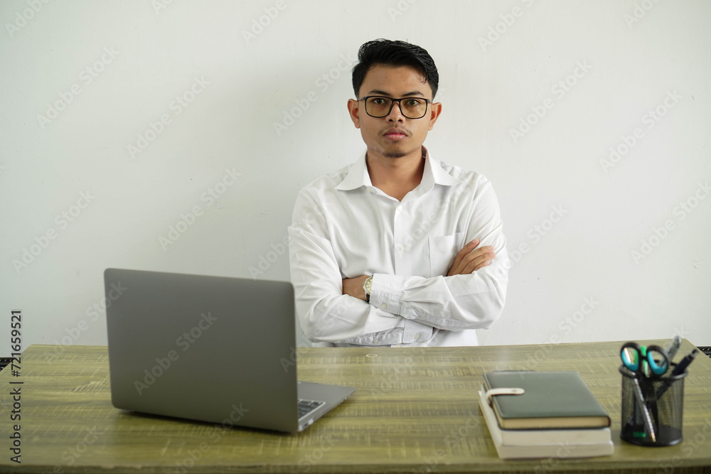 young asian businessman in a workplace feeling upset with crossed hands, wearing white shirt with glasses isolated young asian businessman in a workplace feeling upset with crossed hands, wearing white shirt with glasses isolated