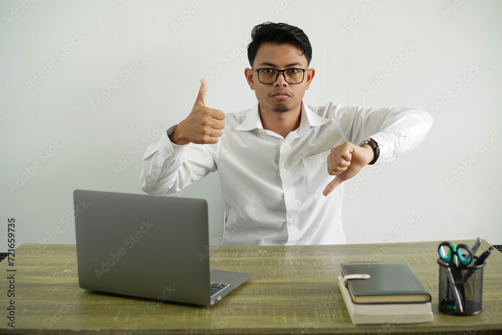 young asian businessman in a workplace making good-bad sign. undecided between yes or not, wearing white shirt with glasses isolated young asian businessman in a workplace making good-bad sign. undecided between yes or not, wearing white shirt with glasses isolated