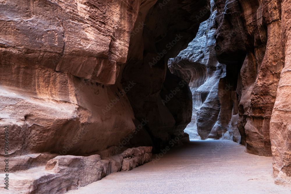 A sandstone canyon path moves between rocks with light breaking through in the distance. Rocks have rich texture from water erosion. No people with leading lines A sandstone canyon path moves between rocks with light breaking through in the distance. Rocks have rich texture from water erosion. No people with leading lines