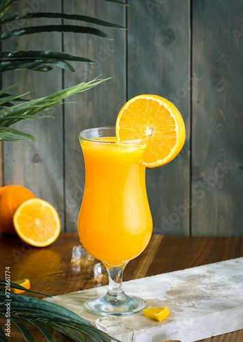 fresh orange juice ,orange in the background and tree part wooden brown floor and green wooden background