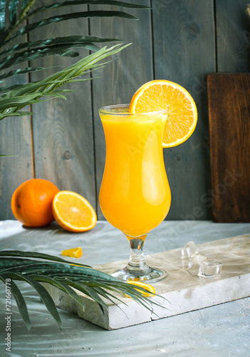 fresh orange juice ,orange in the background and tree part wooden brown floor and green wooden background