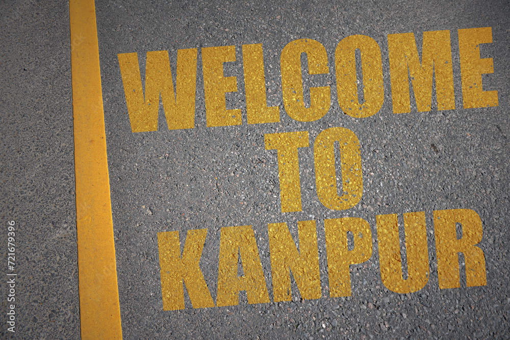 asphalt road with text welcome to Kanpur near yellow line.