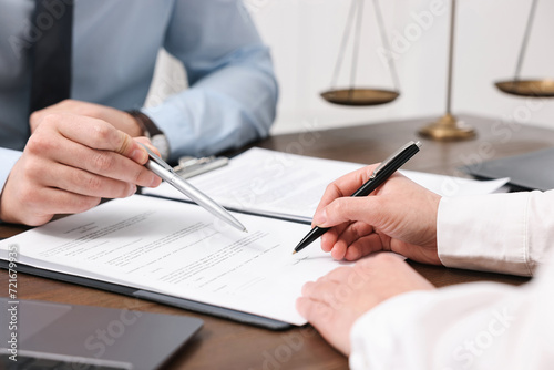 Lawyers working with documents at wooden table indoors, closeup