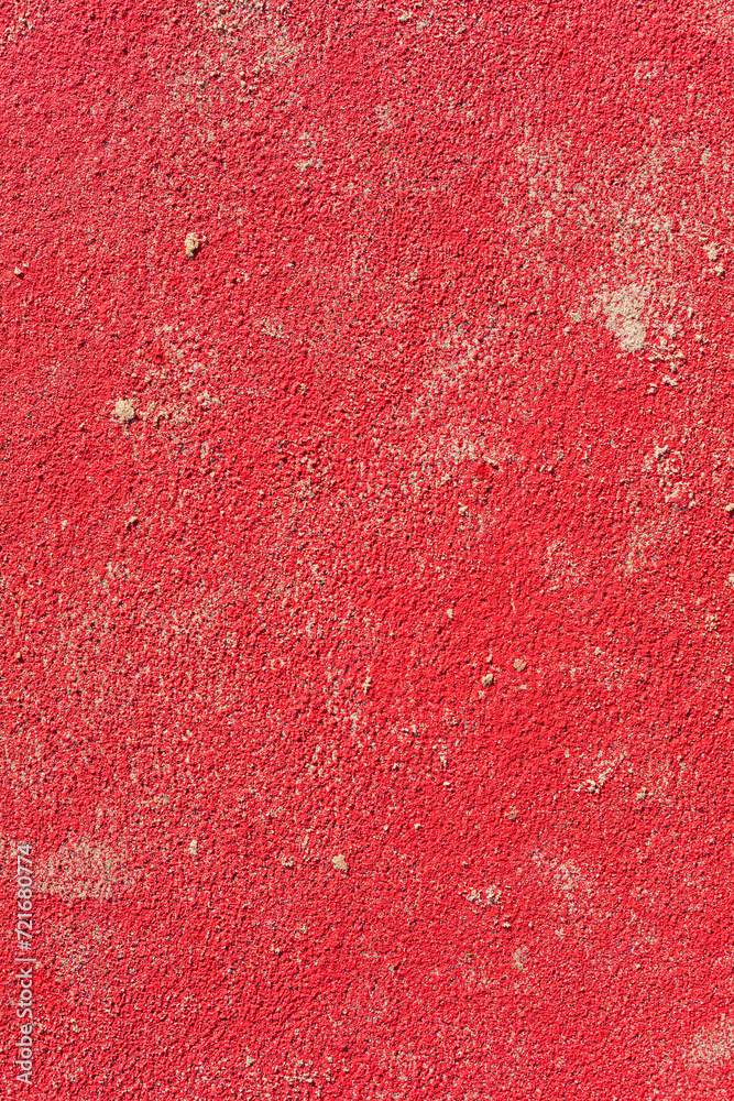 Intense red wall with scattered sand on a sunny day with hard light