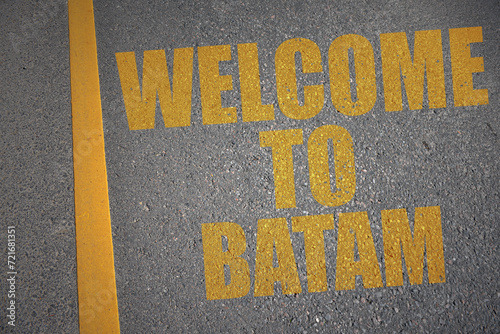asphalt road with text welcome to batam near yellow line. photo