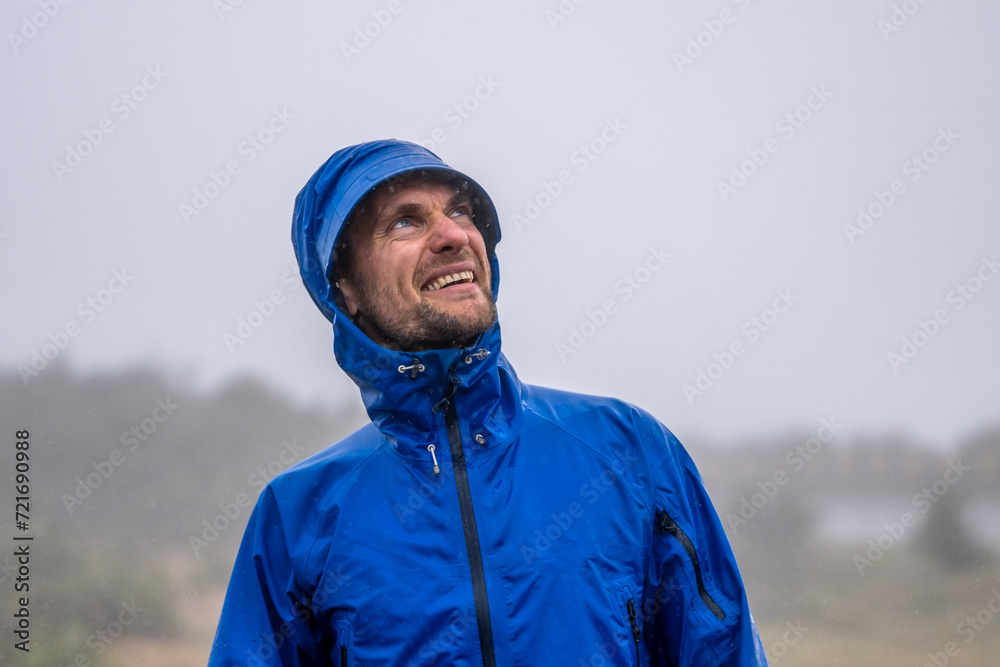 Happy and healthy male tourist staring in sky while smiling and enjoying an active lifestyle in nature and outdoor in the rain. 25 Fontes waterfalls, Madeira Island, Portugal, Europe.
