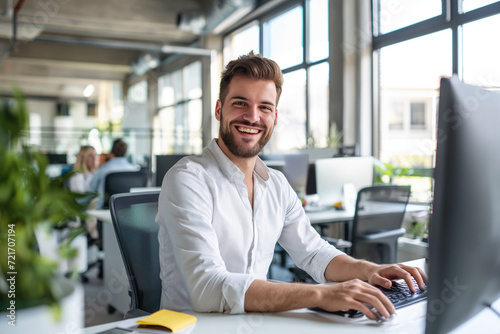  Portrait of Enthusiastic white man Working on Computer in a Modern Bright Office. Confident Human Resources Agent Smiling Happily While Collaborating Online with Colleagues