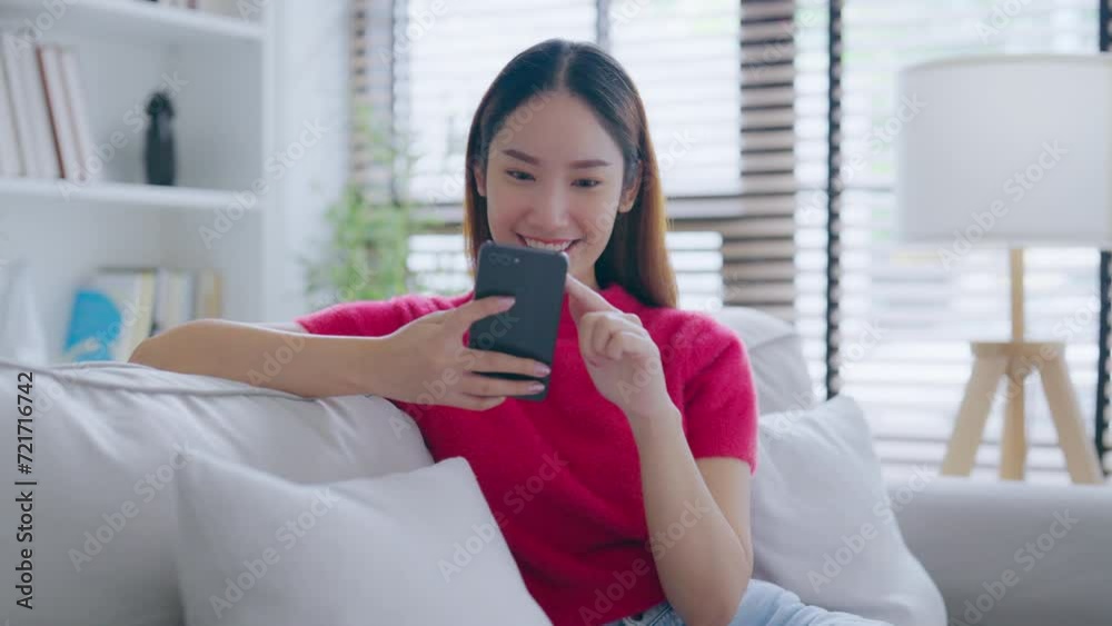 Happy young asian woman relax on comfortable couch at home texting messaging on smartphone, smiling girl use cellphone chatting, online shopping at home, video call communication Happy young asian woman relax on comfortable couch at home texting messaging on smartphone, smiling girl use cellphone chatting, online shopping at home, video call communication