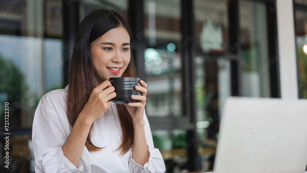 Businesswomen drink coffee and read data on laptop to analysis about new startup in outside office Businesswomen drink coffee and read data on laptop to analysis about new startup in outside office