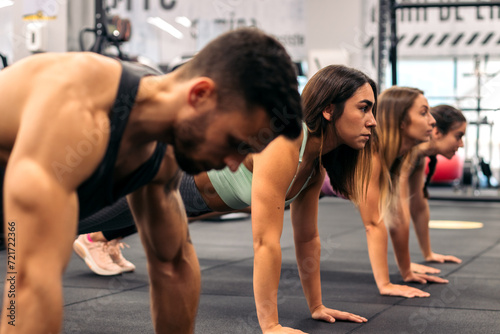 group of young people doing push ups in a gym