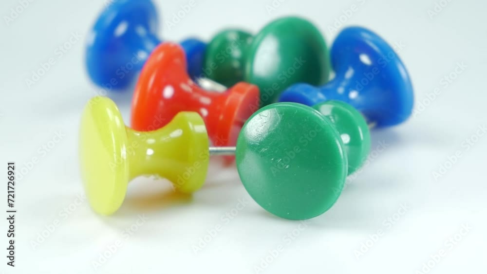 Stationery equipment, colorful plastic pins slow motion on a white background.