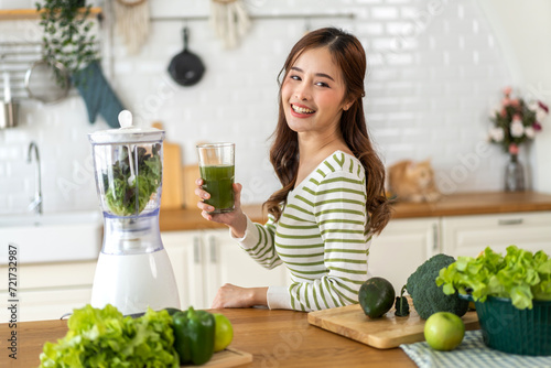 Portrait of beauty healthy asian woman making green vegetables detox cleanse and green fruit smoothie with blender.young girl drinking glass of smoothie, fiber, chlorophyll in kitchen.Diet, healthy