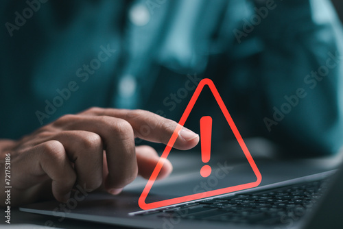 Businessman use laptop with virtual warning sign for caution in investing economic situation warning, Business investment risks.