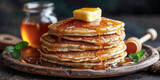 A plate of buttermilk pancakes with a pad of butter and maple syrup or honey dripping down the sides of the stack of pancakes