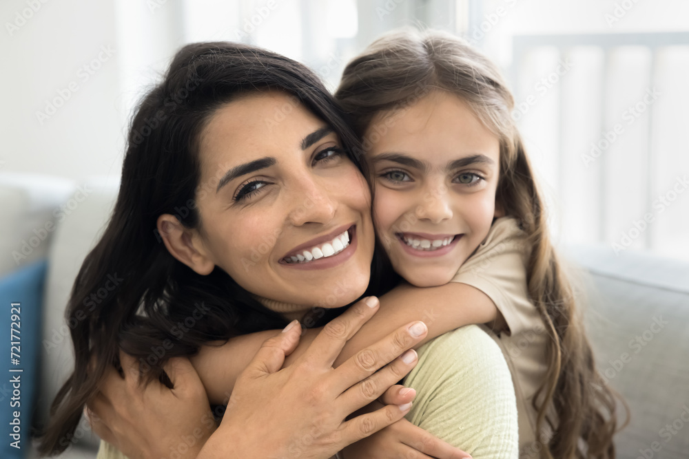 Family portrait on happy Latin mother and cute daughter kid hugging with love, tenderness, affection, posing with face touches, looking at camera, enjoying childhood, motherhood Family portrait on happy Latin mother and cute daughter kid hugging with love, tenderness, affection, posing with face touches, looking at camera, enjoying childhood, motherhood