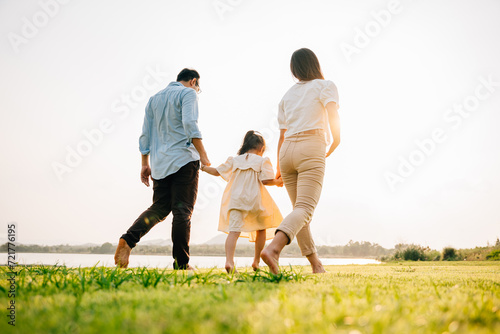 A man and a woman running together in a green field on a summer day, holding hands and feeling the joy of being in love, happy family day, Back view