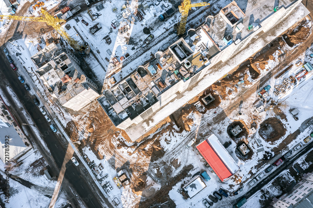construction site in winter. aerial top view of building, cranes, equipment and materials.