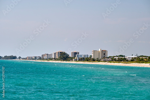 Resort beach with white sand, blue water, tall hotel buildings. Happy people sunbathing and swimming in ocean © bilanol