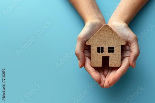Hands holding house on blue background , New home, family home, Real estate agency concept photo