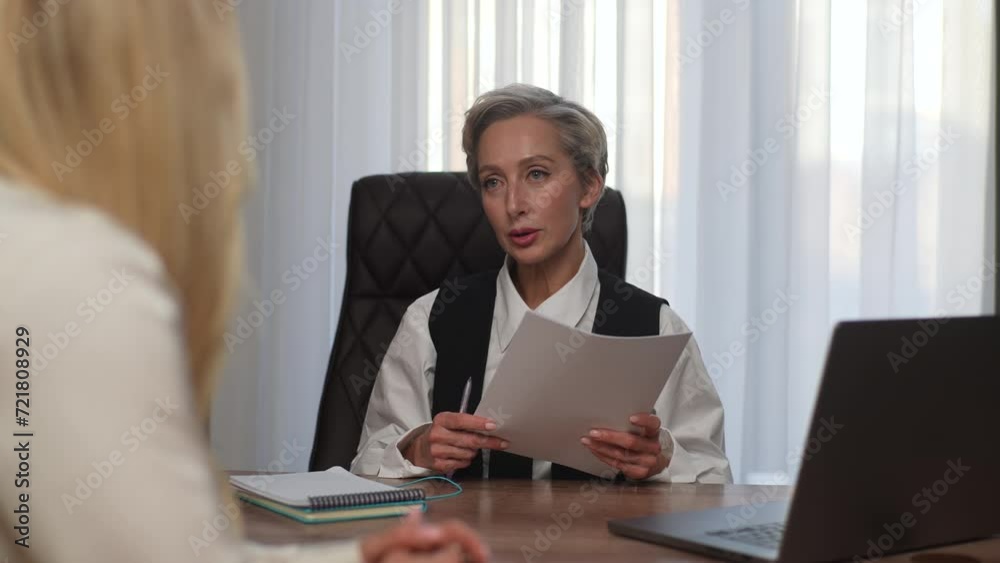 Portrait of serious middle-aged businesswoman finds error mistake in document paper contract with incorrect data in analysis and returning document to unrecognizable female office worker at office. Portrait of serious middle-aged businesswoman finds error mistake in document paper contract with incorrect data in analysis and returning document to unrecognizable female office worker at office.