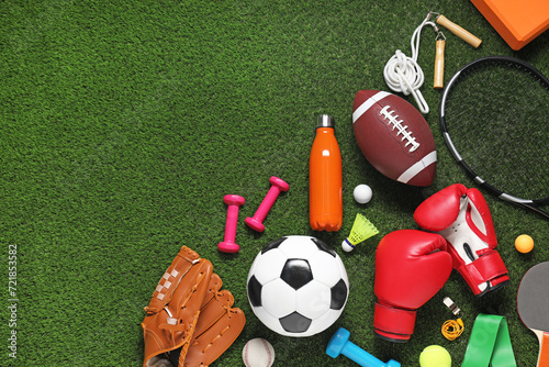 Different sports equipment on green grass, flat lay. Space for text