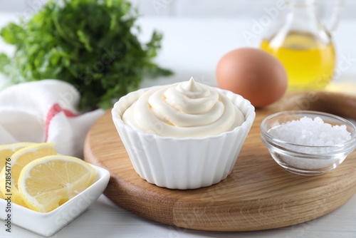 Fresh mayonnaise sauce in bowl and ingredients on table