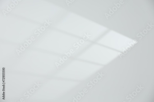 Light and shadow from window on white wall, space for text