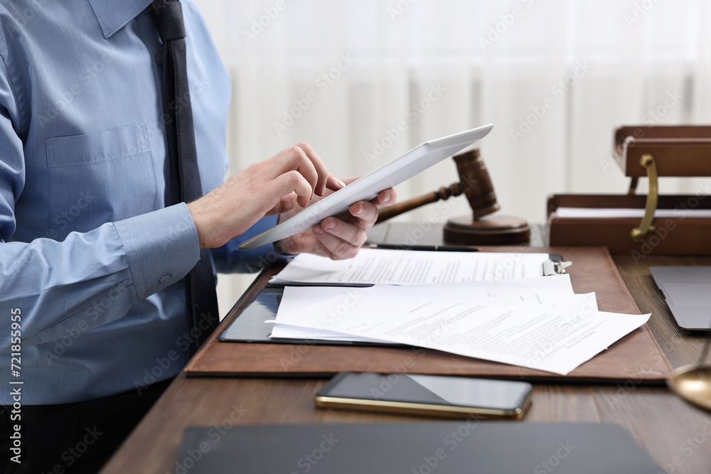 Lawyer using tablet at wooden table, closeup Lawyer using tablet at wooden table, closeup