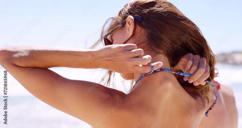 Tying, bikini and woman on beach in summer with fashion, style and costume for swimming in ocean. Person, back and hands knot string of trendy top, bra or outdoor with swimwear on holiday or vacation