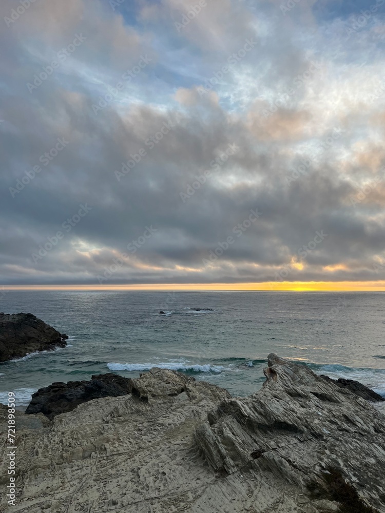 Sunset at the rocky ocean coast, ocean bay, cloudy, golden hour, natural colors