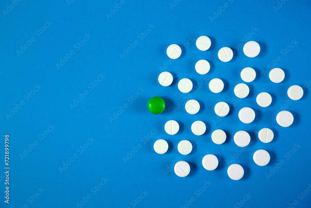 White and green pills lie on a blue monophonic background White and green pills lie on a blue monophonic background