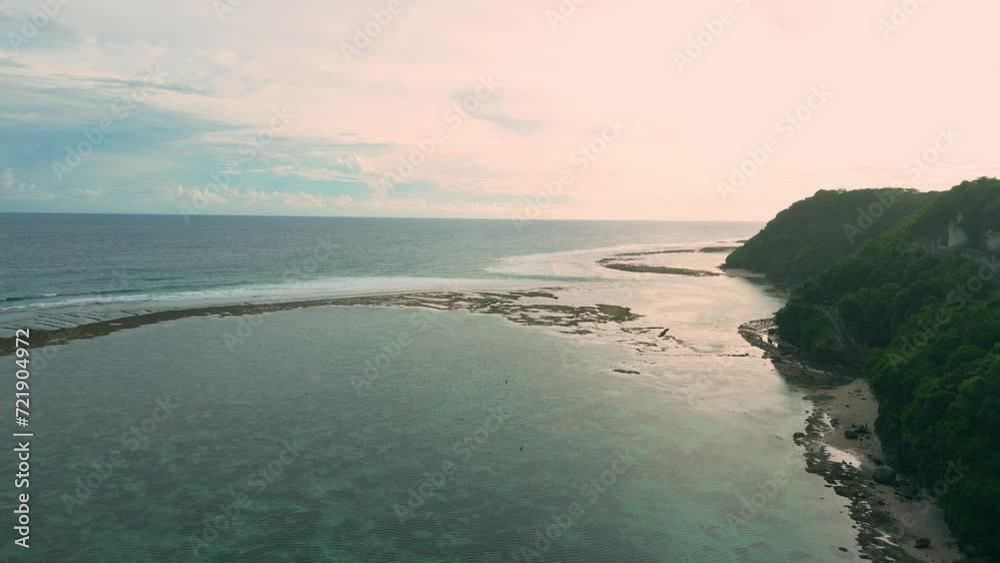 Aerial flight over the ocean with waves against the background of sunset at low tide.