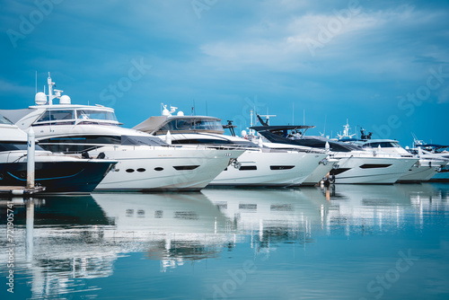 Many white modern yachts moored at the pier of marina.
