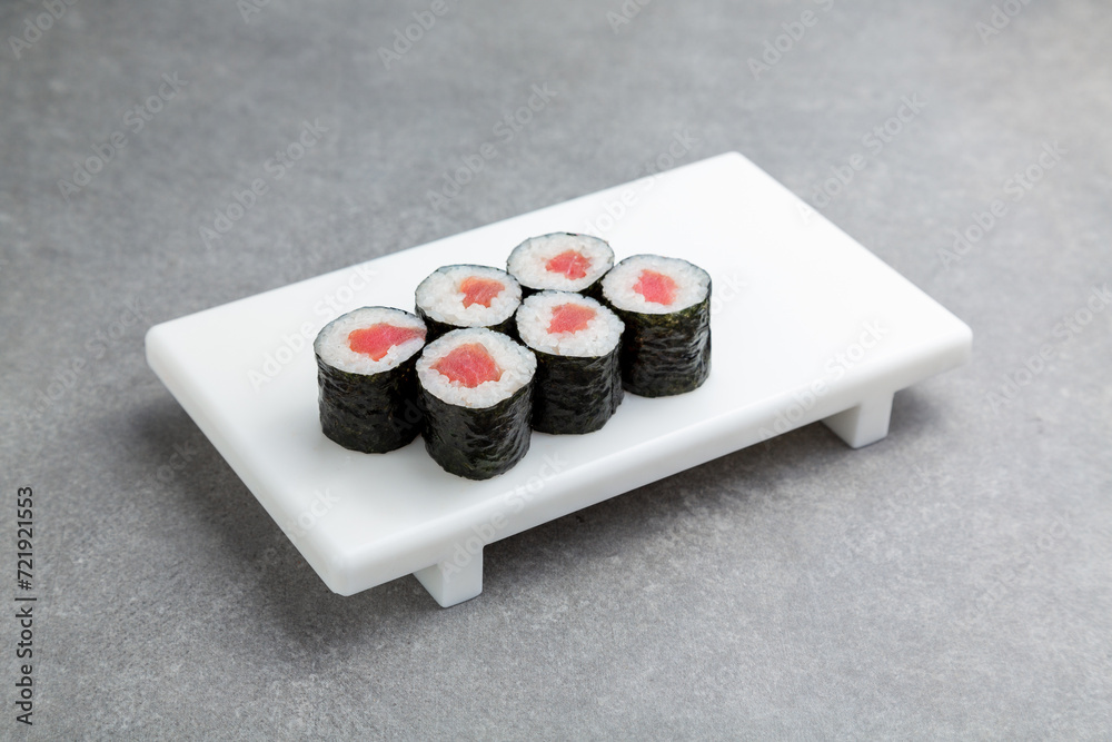 Japanese Sushi roll maki with tuna on a white stand, gray background