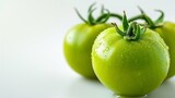 Green fresh tomato on a white background. Raw vegetable closeup with water drops on it