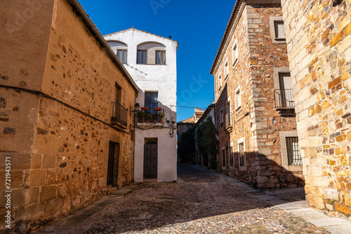 Narrow alley with old houses next to the wall of the medieval city of Caceres