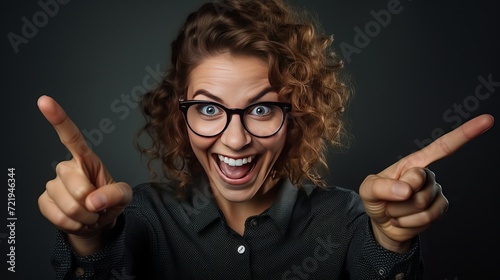 A humorous teacher who wears round glasses and smiles with a stupid face is happy to show something with her pointer on a black chalkboard. photo