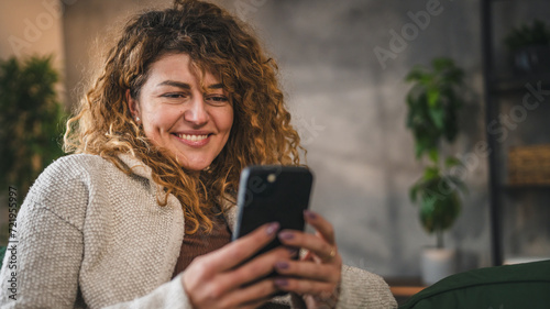 One woman with curly hair at home use mobile phone smartphone sms texting or browse internet