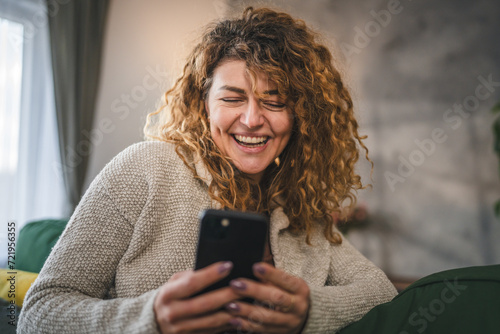One woman with curly hair at home use mobile phone smartphone sms texting or browse internet photo