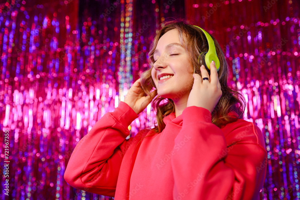 Excited Young Woman Wearing Pink Hoodie Enjoying Song In Wireless Headphones Excited Young Woman Wearing Pink Hoodie Enjoying Song In Wireless Headphones