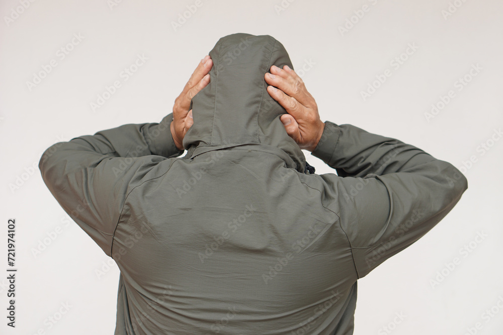 Back view of man wears hoodie, uses his hands to cover ears. Concept, don't want to listen or hear anything. Distressed by noise. Avoid listening to noise of complains or negative words.       