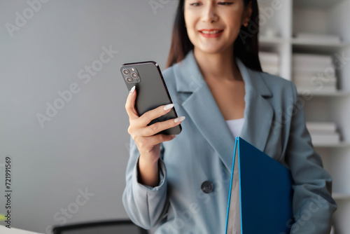 Beautiful female employee using the phone in the office, Young happy businesswoman using computer in office, portrait of a young businesswoman working on a laptop in an office