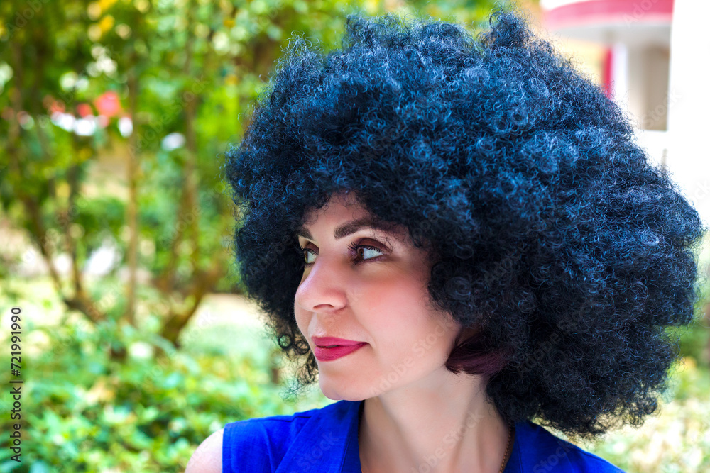 Portrait of a woman with black curly hair and a beautiful smile in a blue dress. Portrait of a woman with black curly hair and a beautiful smile in a blue dress.